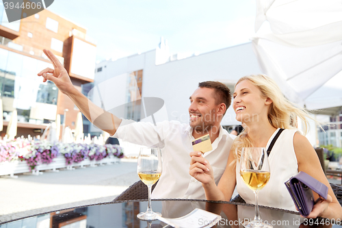 Image of happy couple with wallet paying bill at restaurant