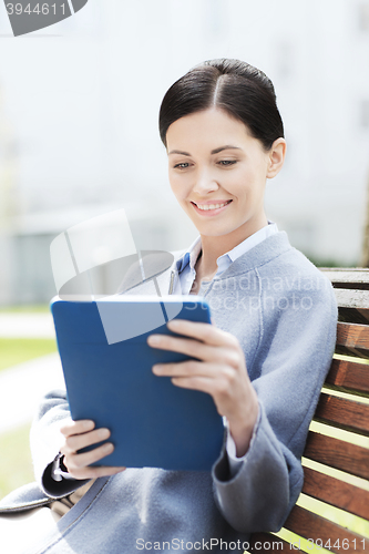Image of smiling business woman with tablet pc in city