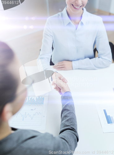 Image of two smiling businesswoman shaking hands in office