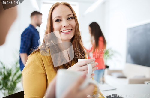 Image of happy creative team drinking coffee at office