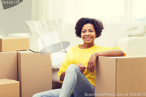 Image of happy african woman with cardboard boxes at home