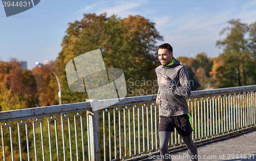 Image of happy young man running over city bridge