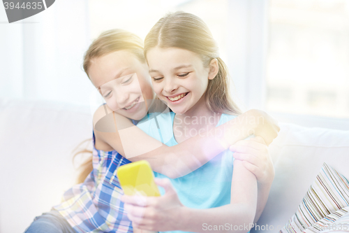 Image of happy girls with smartphone taking selfie at home