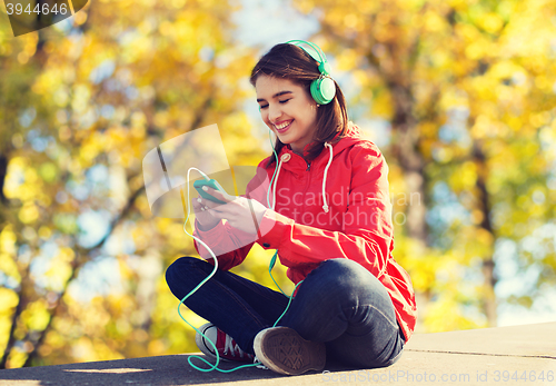 Image of happy young woman with smartphone and headphones
