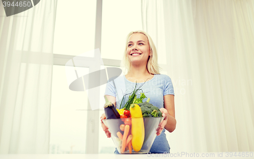 Image of smiling young woman cooking vegetables at home