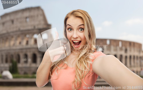 Image of happy woman taking selfie and showing thumbs up