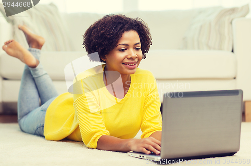 Image of happy african american woman with laptop at home