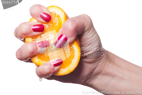 Image of Hand with manicured nails touch an orange on white