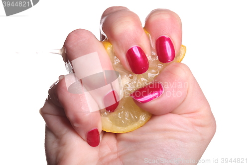 Image of Hand with manicured nails squeeze lemon on white