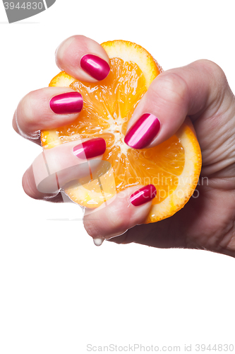 Image of Hand with manicured nails touch an orange on white