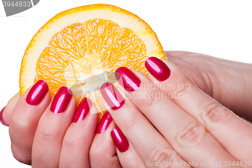 Image of Hand with manicured nails touch an orange on white