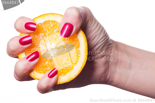 Image of Hand with manicured nails touch an orange on white