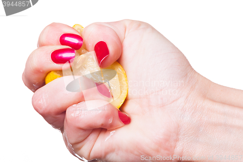 Image of Hand with manicured nails squeeze lemon on white