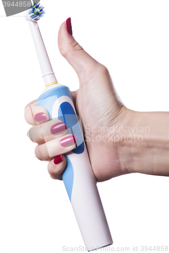 Image of Hand holds electric toothbrush against white