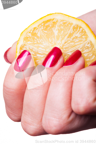 Image of Hand with manicured nails squeeze lemon on white