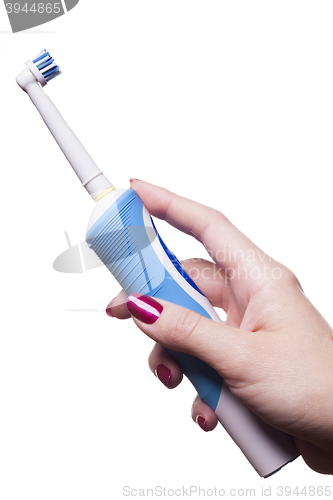 Image of Hand holds electric toothbrush against white