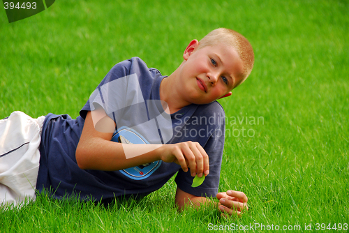 Image of young boy is resting on the grass