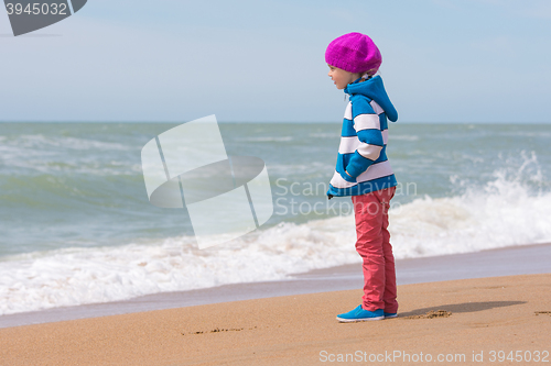 Image of Girl standing on sea beach and looking into the distance