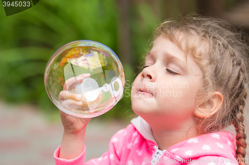 Image of Five-year girl inflates a large circular bubble