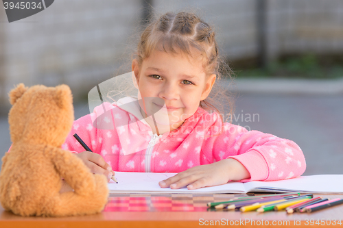 Image of Girl draws with crayons and smile, he looked into the frame