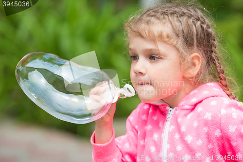 Image of Five-year girl inflates a large soap bubble