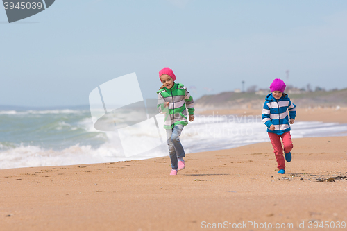 Image of Two girls running on the beach seaside