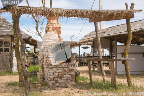 Image of Old Russian stove under thatched shed in the yard outdoors