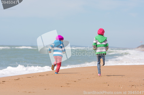 Image of Two girls run a race on the beach seaside