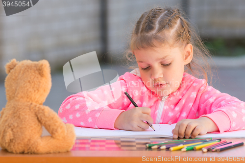 Image of The girl with enthusiasm draws with crayons in the album