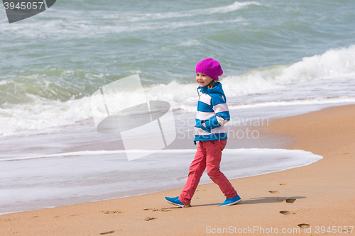 Image of Happy girl walking along coastal sea beach on a warm spring day