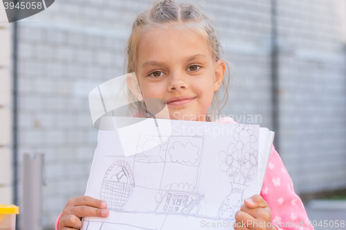 Image of A girl shows a drawing, drawn in pencil