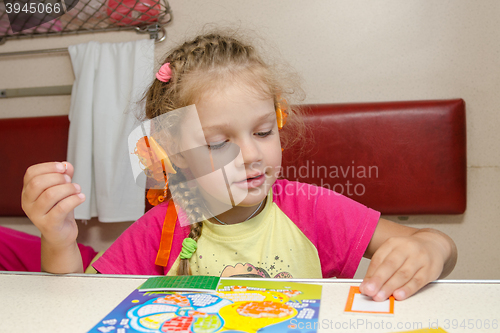 Image of Little girl on the train sits at a table on the lower second-class place car and enthusiastically skin application