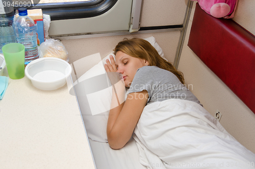 Image of The girl on the train is fast asleep at a lower second-class place car coupe