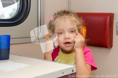 Image of Girl makes faces four years of sitting on the train at the table on the side a place reserved seat