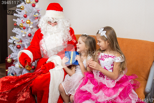 Image of Santa Claus gets gifts from the bag and gives children