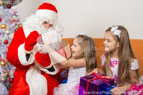 Image of Santa Claus gives presents two sisters