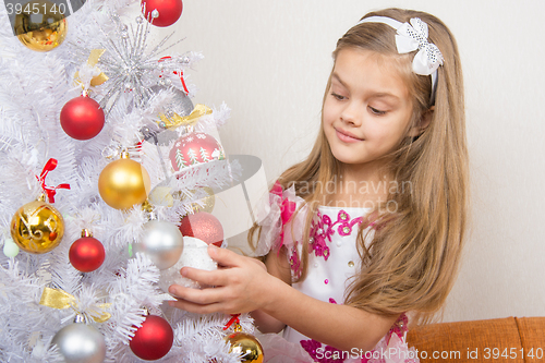 Image of Seven-year girl in a beautiful dress treats Christmas toys