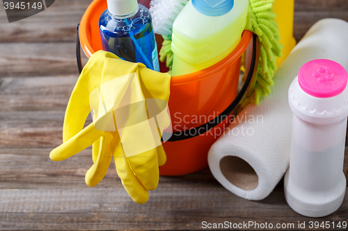 Image of Plastic bucket with cleaning supplies on wood background