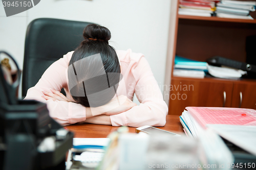 Image of Tired businesswoman sleeping on the desk.