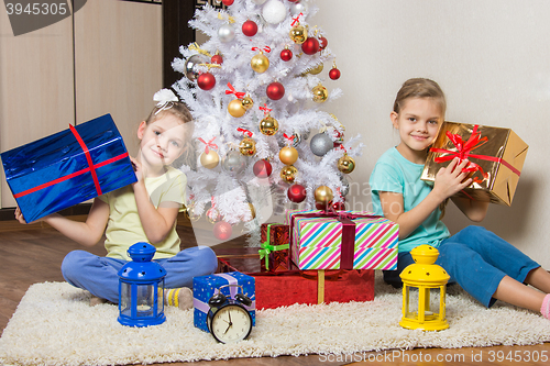 Image of Two little girls with Christmas presents early in the morning sitting by the Christmas tree