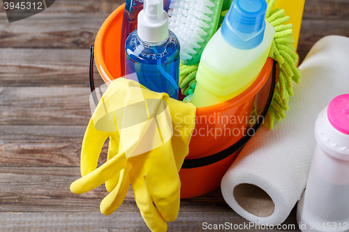 Image of Plastic bucket with cleaning supplies on wood background