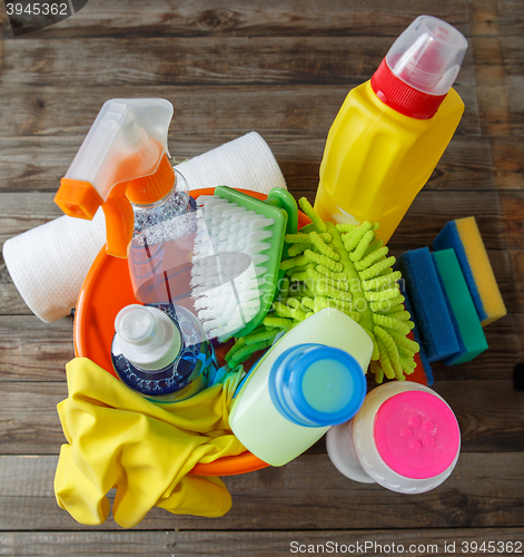 Image of Plastic bucket with cleaning supplies on wood background