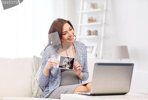 Image of pregnant woman with ultrasound image and laptop