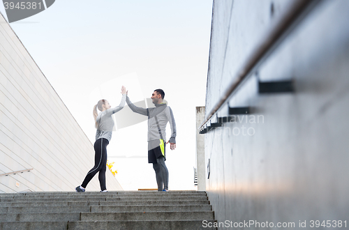 Image of smiling couple making high five on city street