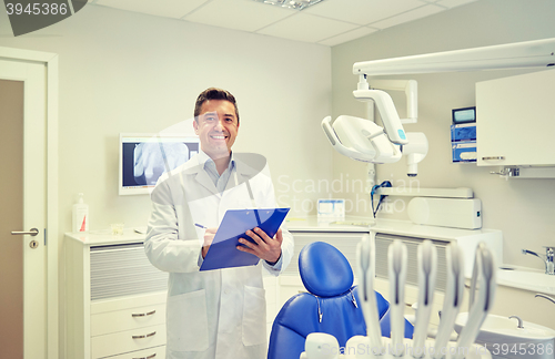 Image of happy male dentist with clipboard at dental clinic