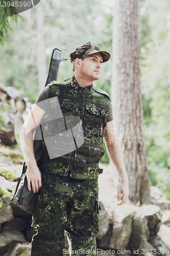 Image of young soldier or hunter with gun in forest