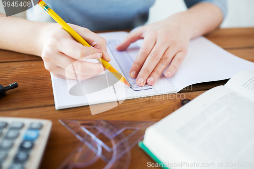 Image of close up of hands with ruler and pencil drawing 