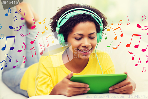 Image of happy african woman with tablet pc and headphones