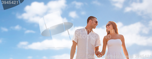 Image of happy smiling couple walking over blue sky