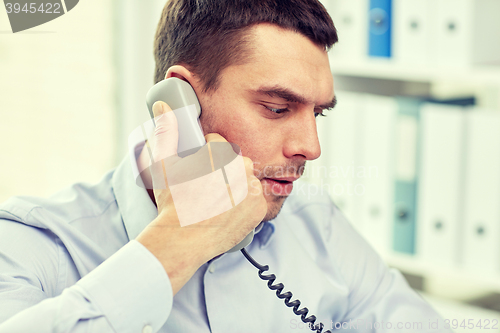 Image of face of businessman calling on phone in office